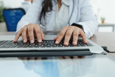 Close-up image of female general practitioner working on computer and entering patients data and diagnosisの写真素材