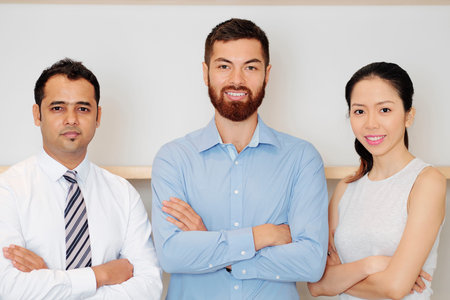 Multi-ethnic confident successful business team crossing arms and looking at camera