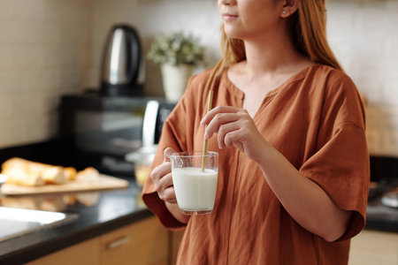 Young woman using reusable bamboo straw when drinking cup of milkの写真素材