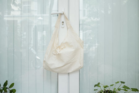 Reusable textile shopping bag hanging on handle of house entrance door
