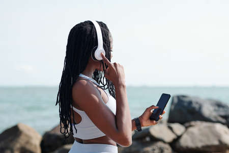 Sportswoman wearing headphones, she is choosing good music, audiobook or podcast for trainingの写真素材