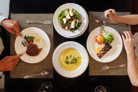 Couple eating delicious food at restaurant table, view from above