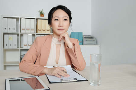 Pensive female human resource manager writing list of job requirementsの写真素材