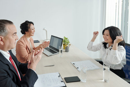 Happy excited young woman celebrating getting dream job after interview with hr manager and head of...
