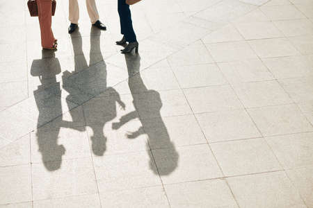 Business people standing outdoors on tile floor and talking about project they are currently working onの写真素材