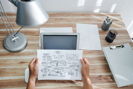 Hands of business person looking at general idea chart in his hands when sitting at home office...