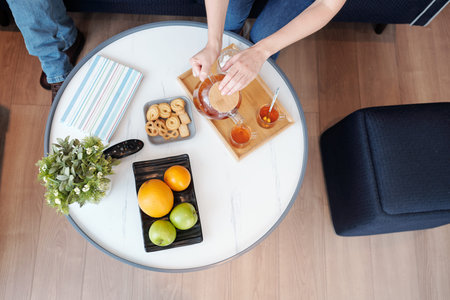 Hands of woman making tea with cookies and fruits for herself and husband, view from the topの写真素材