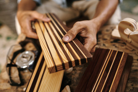 Carpenter showing pieces of walnut and maple wood that have been fused together for making edge...