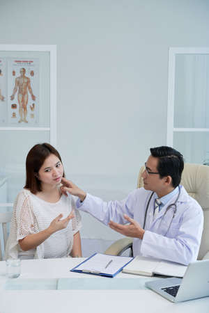 Young woman visiting general practitioner and complaining about pain swelling of her neckの写真素材