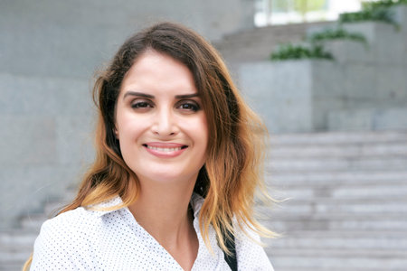 Portrait of smiling attractive businesswoman standing outdoors and smiling at camera