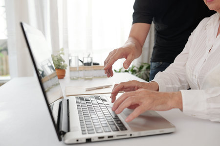 Close-up of woman sitting at the table and typing on laptop she working online with her colleague...