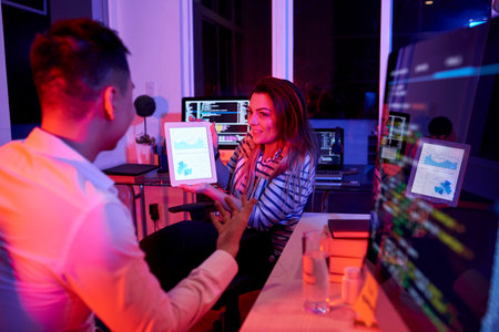 Team of coders discussing reports and statistics when working in office late at night
