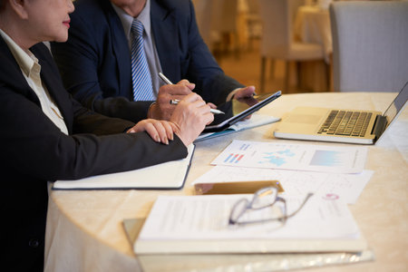 Business executives meeting at restaurant table and discussing data in financial documents and...