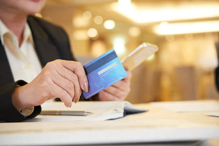 Close-up image of female restaurant owner paying with credit card when ordering staff for kitchen and bar onlineの写真素材