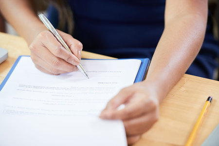 Hands of female entrepreneur working at her office desk and signing contracts