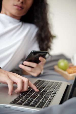 Close-up image of young man texting friends and searching what to watch on tablet computer