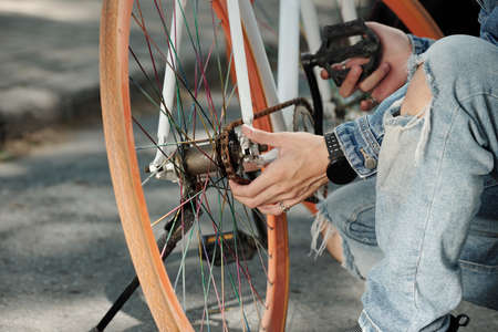 Close-up image of man checking bicycle chain and fixing pedalsの写真素材