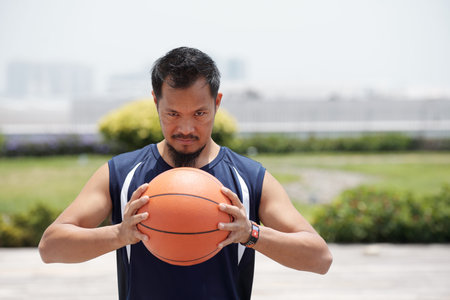 Portrait of determined basketball player squeezing ball and looking at camera