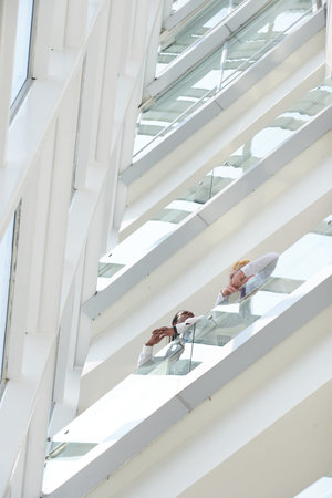 Business partners standing on balcony of modern office building and discussing important issues