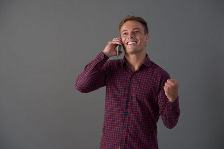 Exited young man receiving good news on phone and making fist bump