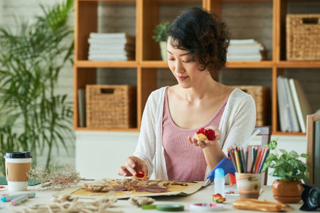 Young woman practicing oshibana art, she is using pressed flowers and other botanical materials to create entire pictureの写真素材