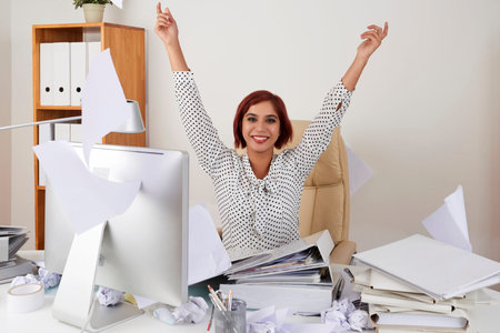 Portrait of happy young female office worker throwing documents celebrating her last day of work