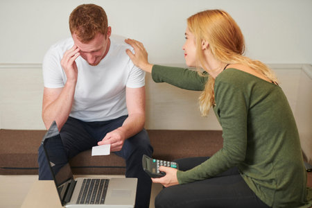 Young woman trying to reassure her husband stressed out over money and big bills he needs to pay
