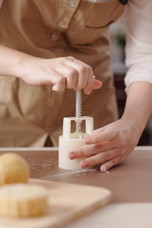 Process of woman making mooncakes with various fillings with help of plastic tool