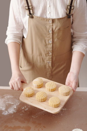 Woman showing wooden board with decorated raw mooncakes she make for mid autumn festivalの写真素材
