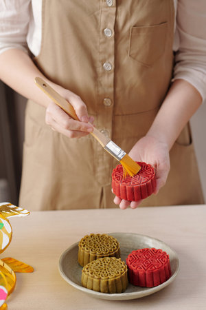 Close-up image of woman glazing homemade mooncakes baked for Vietnamese mid autumn festival