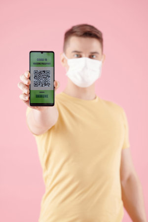 Handsome smiling young man excited to show QR code indicating that he was vaccinated against...