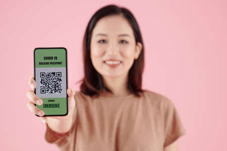 Young woman showing smartphone with QR code after getting shot of vaccine against coronavirusの写真素材