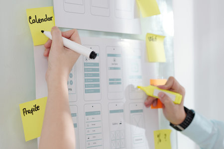UI designers working on mobile application mock-up and writing down ideas on sticky notes