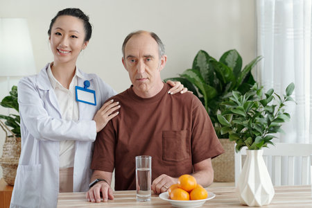 Positive senior man and caregiver visiting him at home