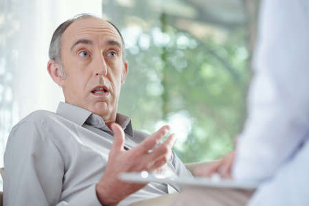 Shocked indignant senior man talking to doctor telling im to stay home and not go anywhereの写真素材