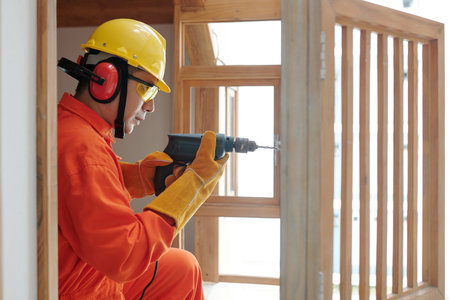 Side view of concentrated builder with drill using self-tapping screw when working with woodの写真素材