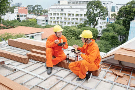 Positive roofing contractors having lunch together, they are eating noodle soup and discussing workの写真素材
