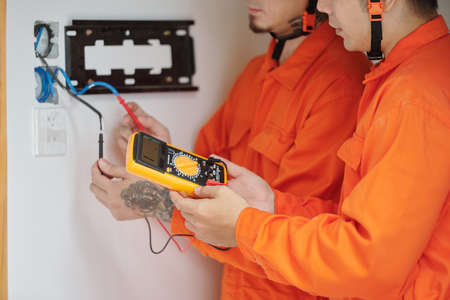 Hands of electricians using multimeter when fixing wiring in house and installing new multimeterの写真素材