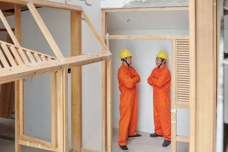Positive confident construction workers standing inside building under construction and discussing work that was doneの写真素材