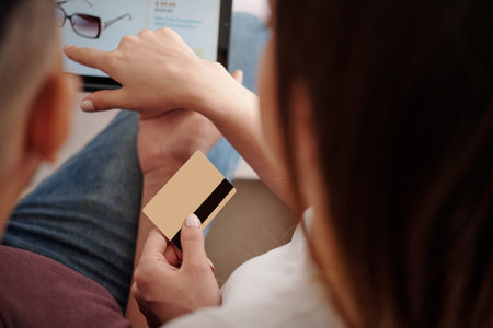 Hands of couple paying with credit card when ordering sunglasses and other accessories in online...