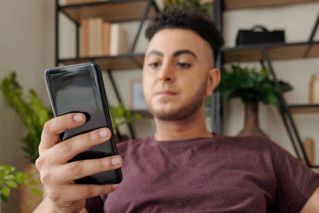 Angry young man reading news on social media or answering text messagesの写真素材