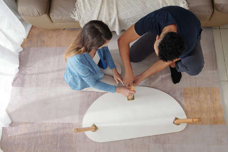 Young couple assembling furniture in new apartment, view from aboveの写真素材