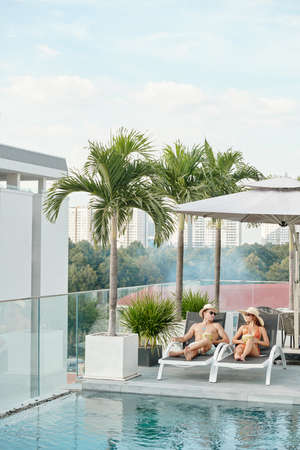 Young couple spending honeymoon at swimming pool on rooftop of hotel buildingの写真素材