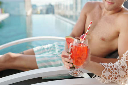 Close-up image of young couple clinking glasses of sweet delicious cocktailsの写真素材