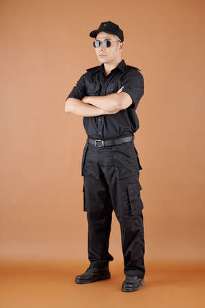 Retail store security guard officer in black uniform standing with arms foldedの写真素材