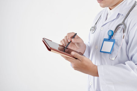 Cropped image of serious general practitioner taking notes on digital tabletの写真素材