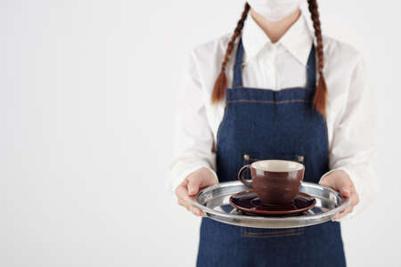 Cropped image of female barista holding tray with cup of coffee or teaの写真素材