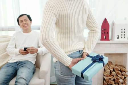Woman hiding Christmas present for husband behind her backの写真素材