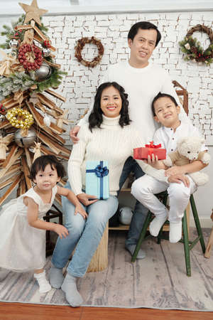 Happy smiling family with presents sitting at Christmas tree at homeの写真素材