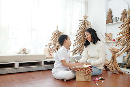 Happy smiling mother and preteen son drawing pictures when decorating house for Christmasの写真素材